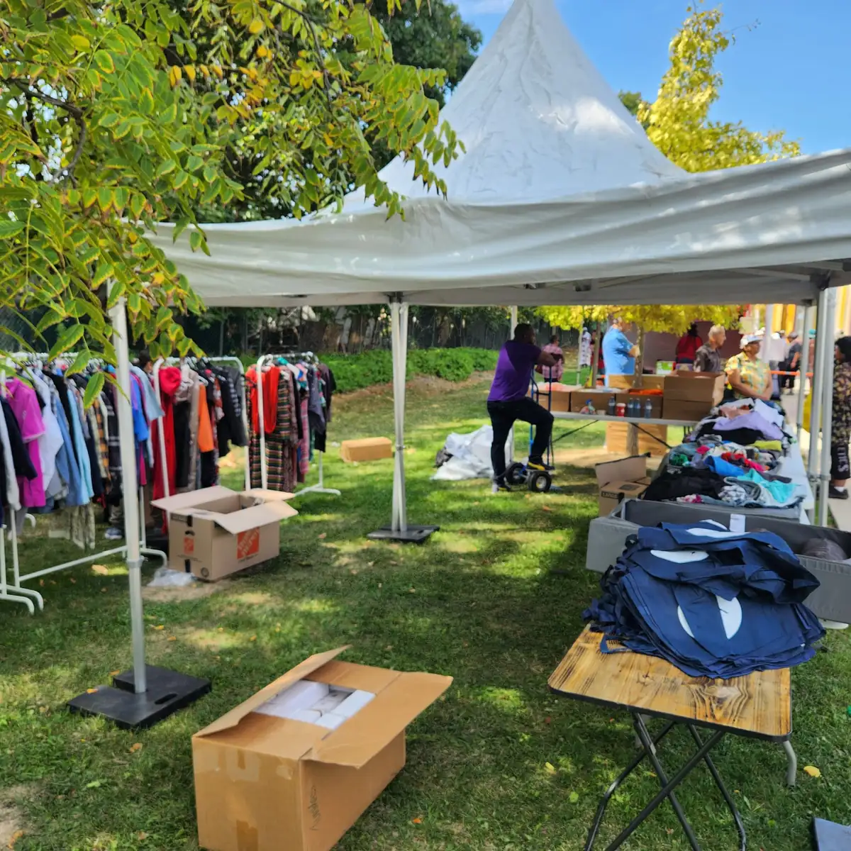 Pop-up clothing event with racks of colourful garments and stacks of branded tote bags