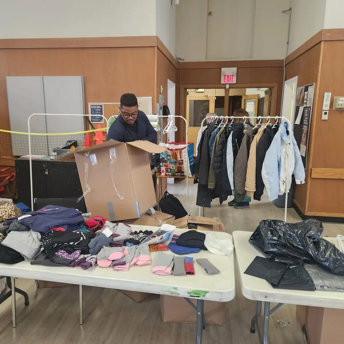 A volunteer organizing cardboard boxes of donated clothing at a distribution event